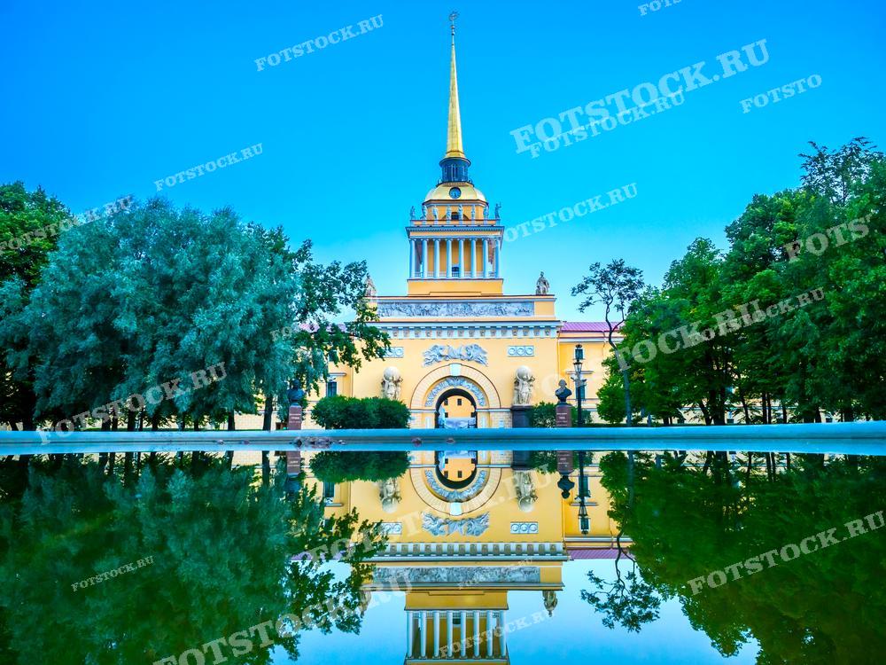 На фотографии изображено здание Адмиралтейства в Санкт-Петербурге, отражающееся в воде. Фотография сделана в летний день. Она подходит для использования в туристических материалах, статьях о достопримечательностях Санкт-Петербурга и иллюстрациях в книгах.